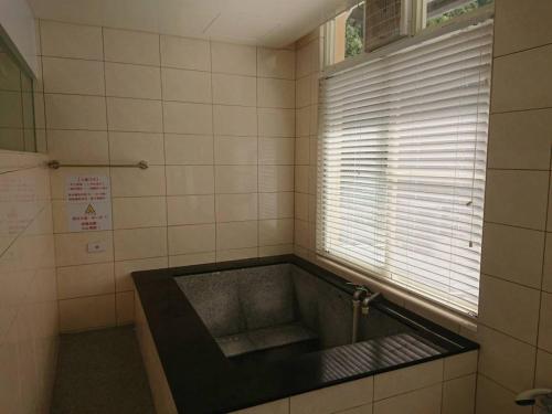 太麻里的住宿－金崙丹堤溫泉會館，带浴缸和窗户的浴室