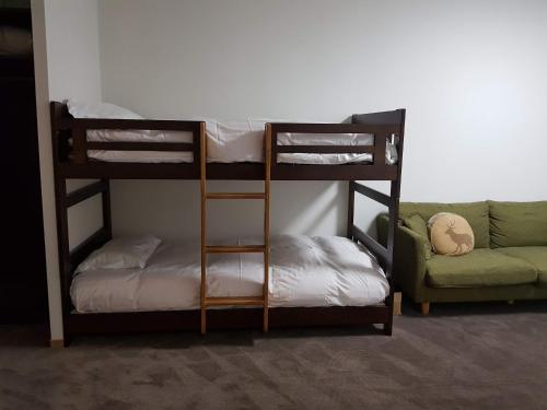a room with three bunk beds and a couch at Chill Madarao in Iiyama