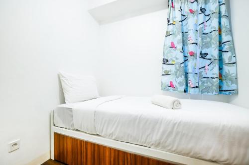 - un lit dans une chambre avec rideau dans l'établissement Modern and Comfy 3BR Bassura City Apartment By Travelio, à Jakarta