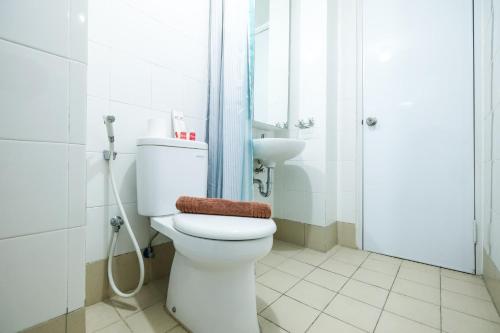 une salle de bain avec toilettes, douche et lavabo dans l'établissement Modern and Comfy 3BR Bassura City Apartment By Travelio, à Jakarta