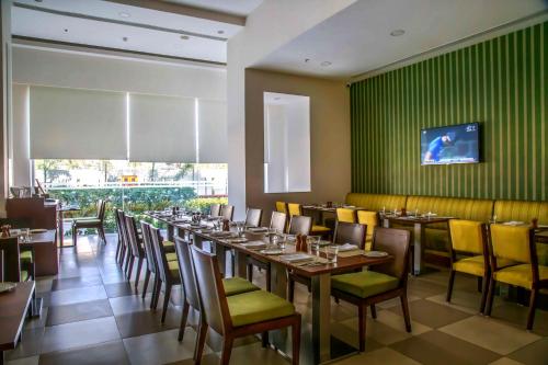 a dining room with tables and chairs and a green wall at Kalyan Grand - a business hotel in Vandalūr