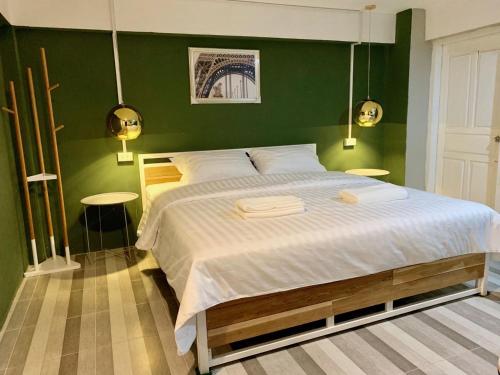 a bedroom with a large bed with green walls at You Empire Hostel & Bar in Pakse