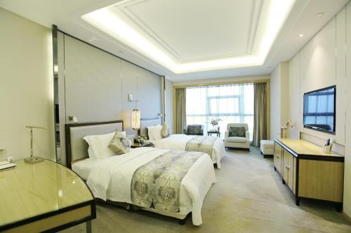 a hotel room with two beds and a television at Empark Hotel Fuzhou Exhibition Centre in Fuzhou