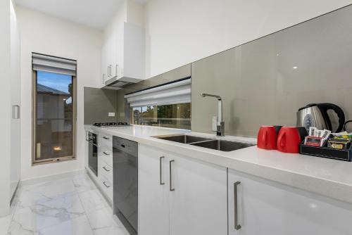 a kitchen with white cabinets and a sink at Melbourne Airport Motel in Melbourne