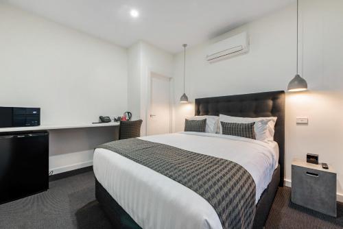a bedroom with a large bed and a desk at Melbourne Airport Motel in Melbourne