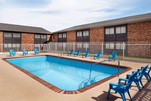 a swimming pool with blue chairs in front of a building at Super 8 by Wyndham Des Moines in Des Moines