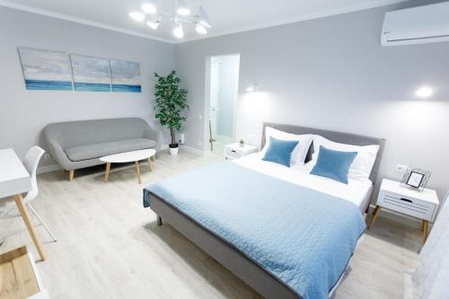 a white bedroom with a bed and a couch at Apart-Hotel "LAVINA" in Sumy