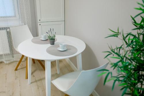 a white table with two cups and two chairs at Apart-Hotel "LAVINA" in Sumy