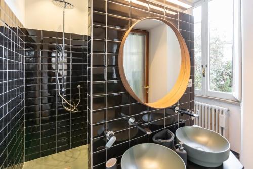 a bathroom with black tiled walls and a round mirror at Lombardia40 Luxury Suites in Rome