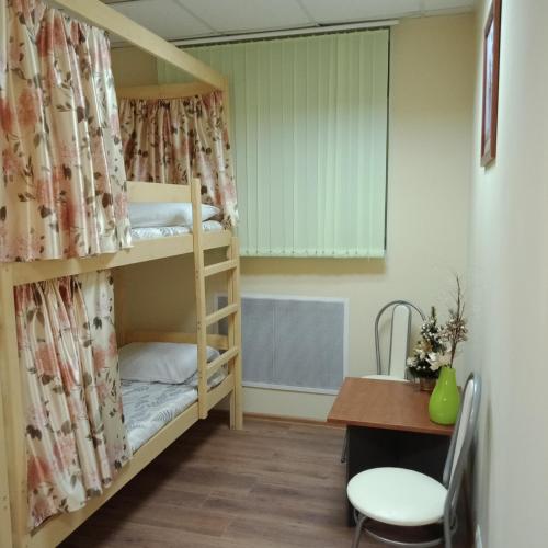 モスクワにあるMilan Hostelの二段ベッド、デスク、テーブルが備わる客室です。