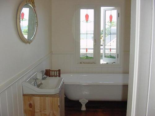 a bathroom with a tub and a sink and a mirror at Captain Lock's Cottage in Rhyll
