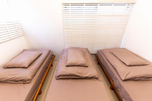 two beds in a room with a window at 九十九里浜で最強に海に近い宿 無料の最新カラオケ&bbq付き in Miyamae