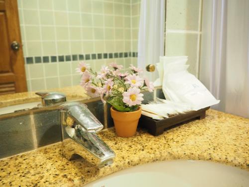 Un mostrador de baño con fregadero y un jarrón de flores en Your Place Inn, en Karon Beach