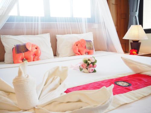 a white bed with two stuffed elephants on it at Your Place Inn in Karon Beach