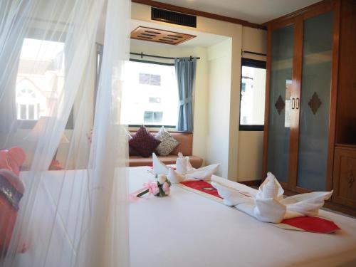 a bedroom with a bed with white curtains and dolls on it at Your Place Inn in Karon Beach