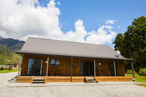 a cabin with a porch and chairs in front of it at Franz Alpine Retreat in Franz Josef