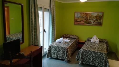 a green room with a bed and a mirror at Hotel Don Pelayo in Arbós