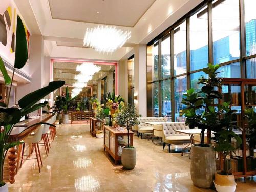 成都Chengdu Taikoo Li Chunxi Mercure Hotel的大厅里摆满了植物和桌椅