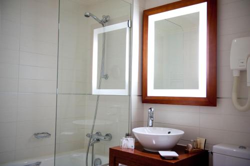 a bathroom with a sink and a glass shower at Westside Arc de Triomphe Hotel in Paris