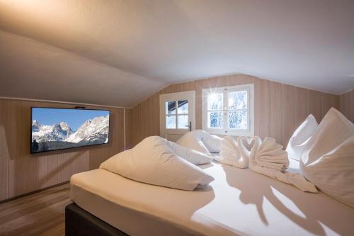 sypialnia z łóżkiem z białymi poduszkami i telewizorem w obiekcie Kaiser Chalet w mieście Going