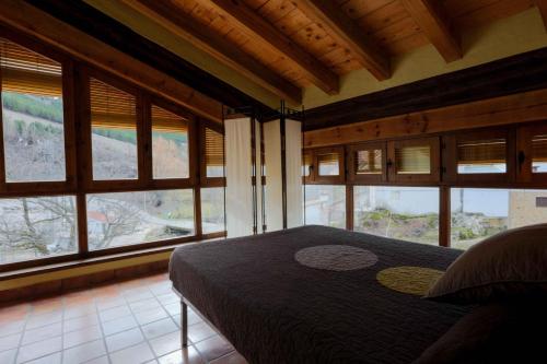 ein Schlafzimmer mit einem Bett in einem Zimmer mit Fenstern in der Unterkunft Casas Rurales El Nacimiento in Santiago-Pontones