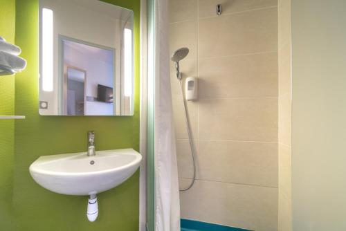 La salle de bains est pourvue d'un lavabo, d'un miroir et d'une douche. dans l'établissement B&B HOTEL CHATEAUROUX Déols, à Déols