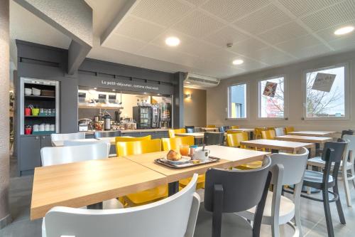 DéolsにあるB&B HOTEL CHATEAUROUX Déolsの木製のテーブルと黄色い椅子のあるレストラン