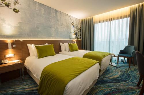 two beds in a hotel room with green sheets at ibis Styles Izmir Bornova in Izmir