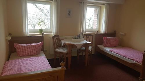 Cette chambre comprend 2 lits, une table et 2 fenêtres. dans l'établissement Zimmervermietung BredyGbR, à Querfurt