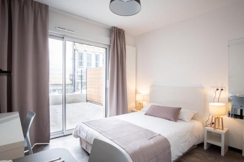 a white bedroom with a bed and a balcony at Student Factory Bordeaux Armagnac in Bordeaux