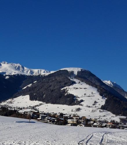 a snow covered mountain with a small town on it at Barschtlerhof in Axams