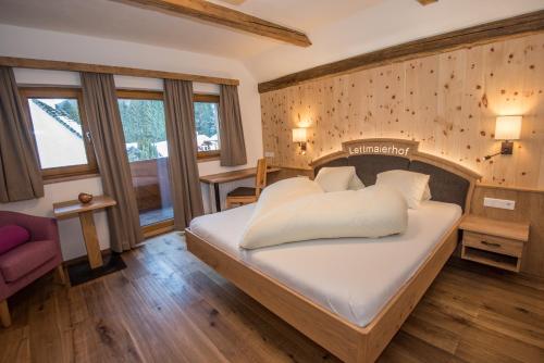 a bedroom with a large bed and a chair at Lettmaierhof in Haus im Ennstal