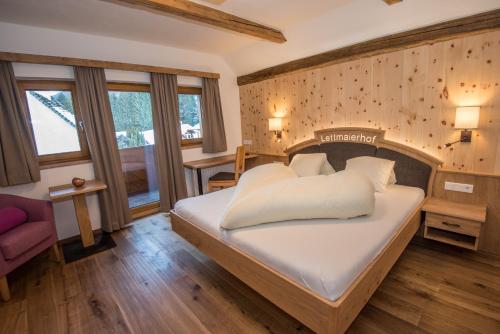 ein Schlafzimmer mit einem großen Bett und einem Stuhl in der Unterkunft Lettmaierhof in Haus im Ennstal