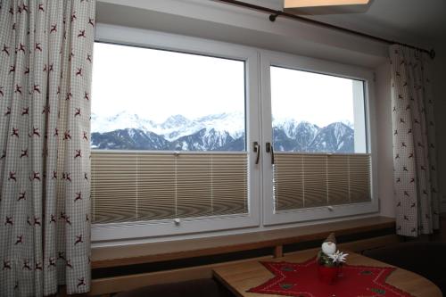 a room with two windows with snow covered mountains at Ritterhof in Fiss