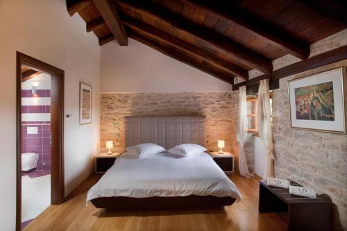 a bedroom with a large bed and a brick wall at Villa Poropati, Grožnjan, Istria - Luxury Countryside Estate for up to 19 persons - Large pool of 80m2 with kids section in Grožnjan
