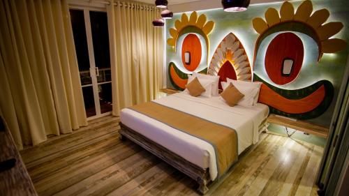 1 dormitorio con 1 cama y una gran pintura en la pared en 18 Faces with free drop off to Galle Fort by TukTuk en Galle