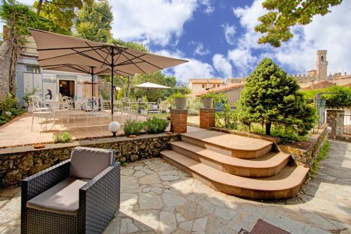 eine Terrasse mit einer Bank und einer Treppe mit einem Sonnenschirm in der Unterkunft Albergo Etruria in Volterra