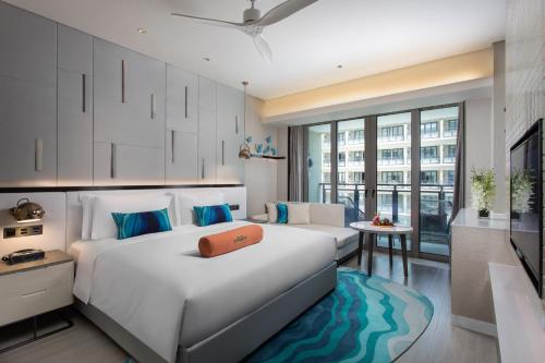 um quarto com uma grande cama branca e um sofá em Wingate by Wyndham Sanya Luhuitou em Sanya