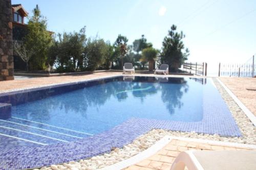 a large swimming pool with two chairs in a yard at LAS MORADITAS, CHALET con PISCINA PRIVADA in Adeje