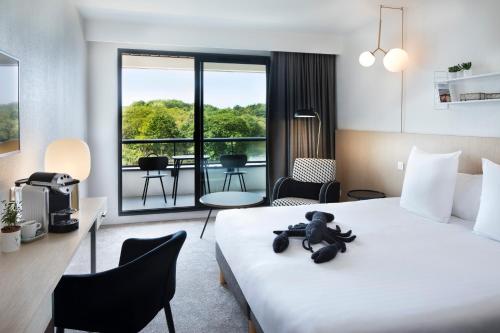 a hotel room with a bed with a teddy bear on it at Best Western Plus Hotel les Rives du Ter in Larmor-Plage