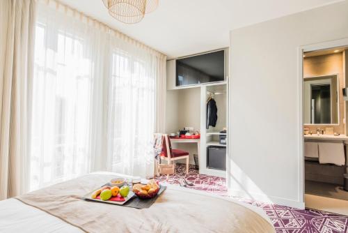 a bedroom with a tray of fruit on a bed at Mercure Paris Pont de Levallois Neuilly in Levallois-Perret