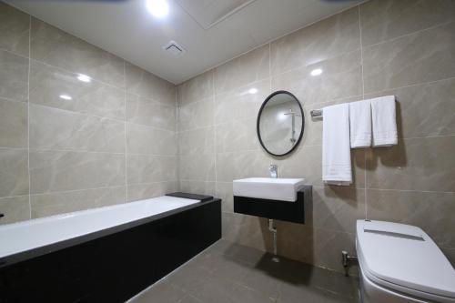 a bathroom with a tub and a sink and a mirror at Hotel Artheim in Gwangju