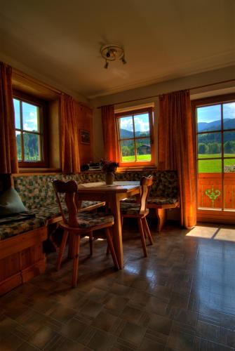 a dining room with a table and chairs and windows at Haus Schatzbergblick in Oberau