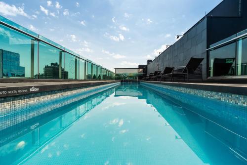 a large swimming pool with glass windows on a building at Hotel Laghetto Moinhos in Porto Alegre