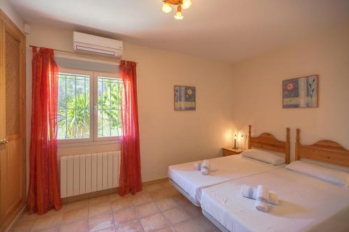 a bedroom with two beds with red curtains and a window at Villas Guzman - Carlos in Calpe
