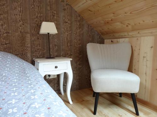 a bedroom with a chair next to a bed and a lamp at Maison d'hôtes l'Arnica in La Bréole