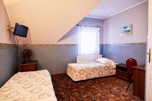 a hotel room with two beds and a tv at Zielony Zakątek in Ostrołęka