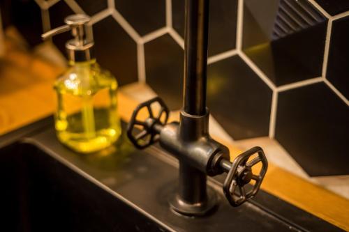 a sink with a faucet and a bottle of soap at BpR Emerald City Apartment in Budapest