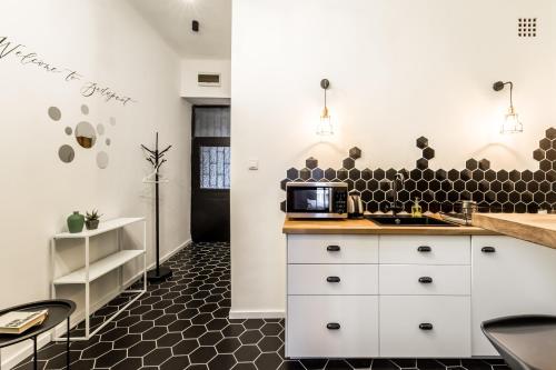 a kitchen with white cabinets and a black tile floor at BpR Emerald City Apartment in Budapest