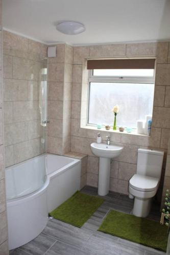 a bathroom with a tub and a toilet and a sink at 25 Idmiston Road in London
